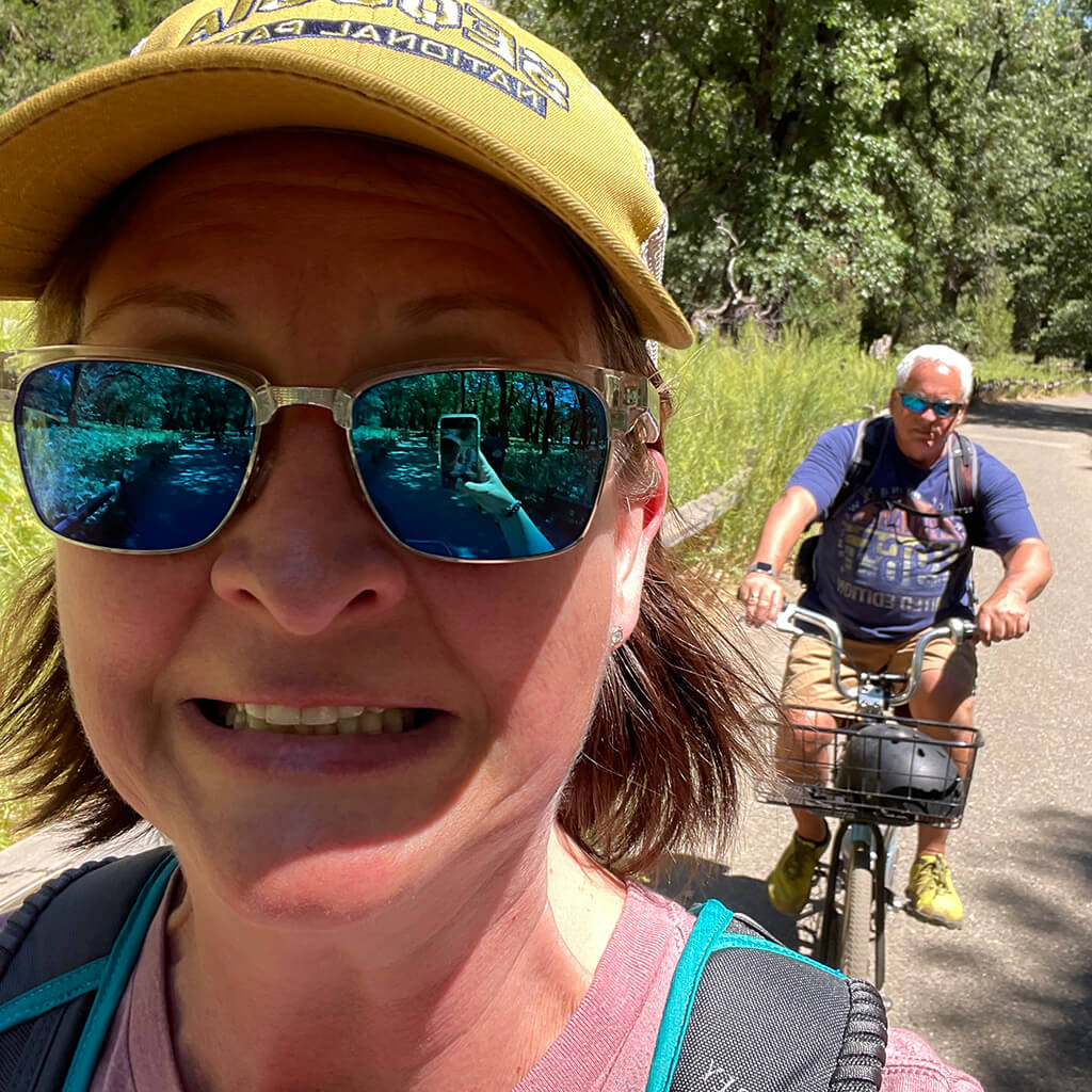 Holly riding bikes in the woods with a friend. She looks like she is going to crash.