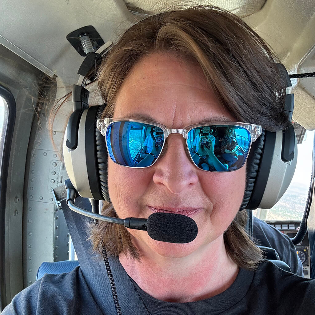 Holly wearing aviator headset inside a helicopter on vacation.